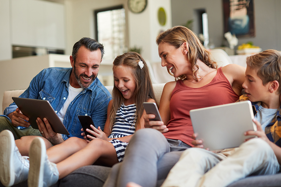Family on couch looking at laptops and tablets High Speed Internet Service